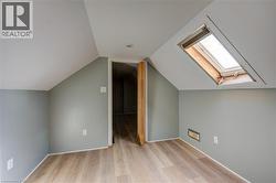Bedroom 2 featuring a skylight, wood-finish flooring, recessed lighting, and sloped ceilings - 