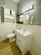 Unit 1A - 4 Pc Bathroom featuring wood-finish flooring, white square wall tile, and a white vanity with integrated sink - 