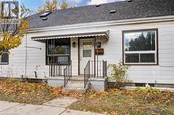Unit 1B entrance; White siding exterior with dark brown trim windows - 