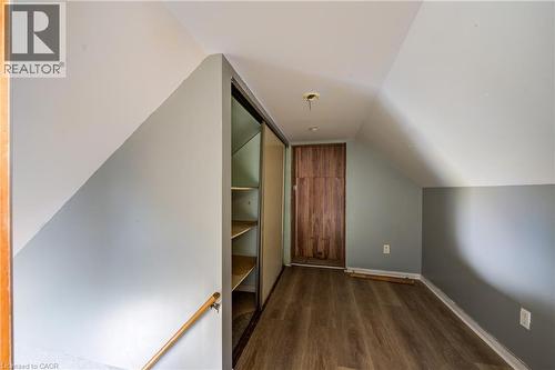 Loft space featuring wood-finish flooring, built-in shelving with sliding doors, a natural wood door, and sloped ceilings - 1 Rathgar Street, London, ON - Indoor Photo Showing Other Room