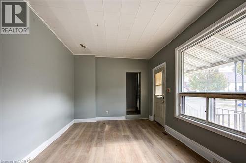 Spacious living room room featuring light gray walls, wood-finish flooring, a large window, white trim throughout, and a paneled ceiling - 1 Rathgar Street, London, ON - Indoor Photo Showing Other Room