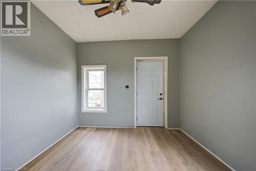 Unit 1A Living Room; Light gray walls complement the wood-finish flooring in this room featuring a white paneled door, a single window with white trim, and an overhead ceiling fan - 1 Rathgar Street, London, ON - Indoor Photo Showing Other Room