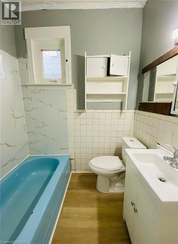 Unit 1A - 4 Pc Bathroom featuring a blue bathtub, white vanity with integrated sink, white toilet, and wood-finish flooring - 1 Rathgar Street, London, ON - Indoor Photo Showing Bathroom