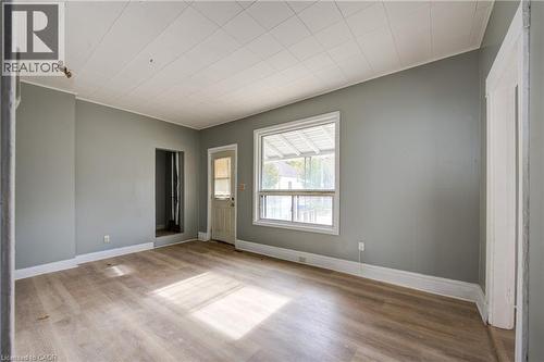 Spacious living room featuring wood-finish flooring, light gray walls, a white paneled ceiling, and a prominent window - 1 Rathgar Street, London, ON - Indoor Photo Showing Other Room