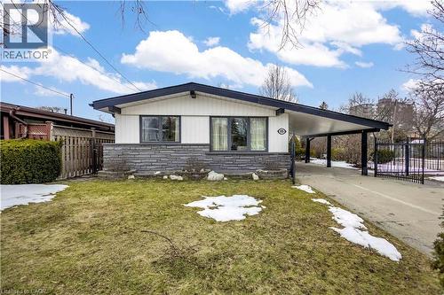 Exterior featuring a white facade with dark trim, stone veneer detailing, a covered carport, and a concrete driveway - 85 Ranchdale Drive, Hamilton, ON - Outdoor