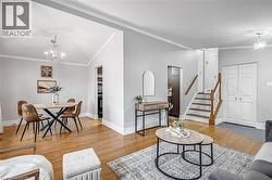 Open-concept living area featuring hardwood flooring, light gray wall tones, and white crown molding - 