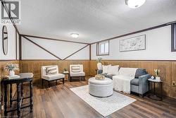 Finished lower level featuring wood-finish flooring, paneled walls, white ceilings, and recessed windows - 