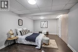 Spacious room featuring wood-finish flooring, light grey painted walls, and a dropped ceiling with integrated lighting - 