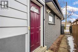 Exterior entry featuring a red paneled door with an arched transom window, white horizontal siding, and a contrasting gray brick facade - 
