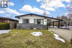 Exterior featuring a white facade with dark trim, stone veneer detailing, a covered carport, and a concrete driveway - 