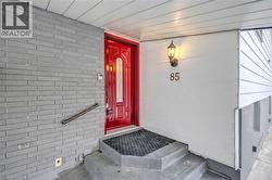 Red entry door with frosted glass panel, flanked by grey brick and white siding - 