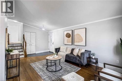 Living area featuring wood-finish flooring, light gray wall tones, white trim, and a white front entry door with decorative glass - 85 Ranchdale Drive, Hamilton, ON 