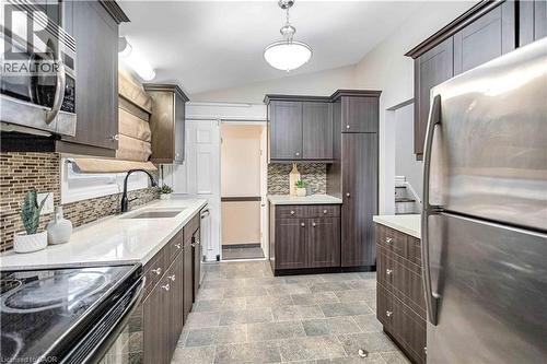 Contemporary kitchen featuring wood-finish cabinetry, light-toned countertops, and a mosaic tile backsplash - 85 Ranchdale Drive, Hamilton, ON 