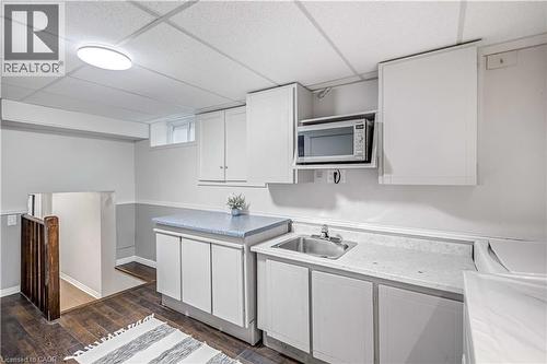 Compact kitchen area featuring white cabinetry, a built-in microwave, a stainless steel sink, and light-toned countertops - 85 Ranchdale Drive, Hamilton, ON 