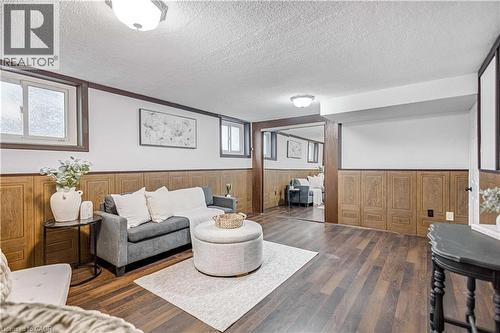 Spacious room featuring wood-finish flooring, wood paneling, white walls, and recessed windows - 85 Ranchdale Drive, Hamilton, ON 