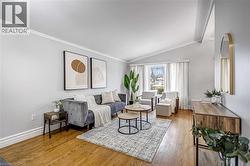 Spacious living area featuring wood-finish flooring, white crown molding, and a vaulted ceiling - 
