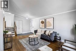 Living area featuring wood-finish flooring, light gray wall tones, white trim, and a white front entry door with decorative glass - 