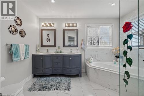 Spacious bathroom featuring a dual vanity with a deep blue finish, a corner soaking tub with marble-look tile surround, and a walk-in glass shower enclosure - 79 Holbrook Crescent, Cambridge, ON - Indoor Photo Showing Bathroom