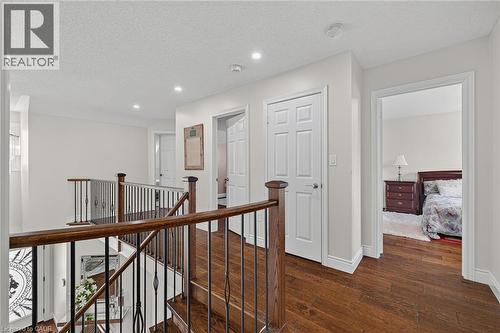 Upper-level hallway featuring rich wood-finish flooring, white trim, recessed lighting, and a dark wood and wrought iron staircase railing - 79 Holbrook Crescent, Cambridge, ON - Indoor Photo Showing Other Room
