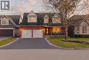 Brick and siding exterior featuring a double-car garage with white doors, a paved driveway, and a covered front porch - 79 Holbrook Crescent, Cambridge, ON  - Outdoor With Facade 