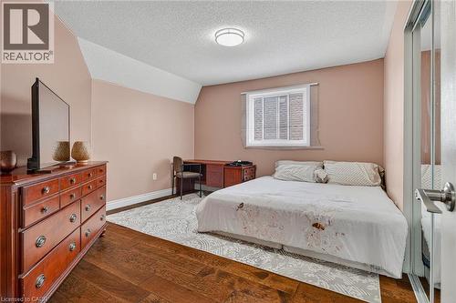 Bedroom featuring wood-finish flooring, a window with a white frame, and a built-in sliding closet - 79 Holbrook Crescent, Cambridge, ON - Indoor Photo Showing Bedroom