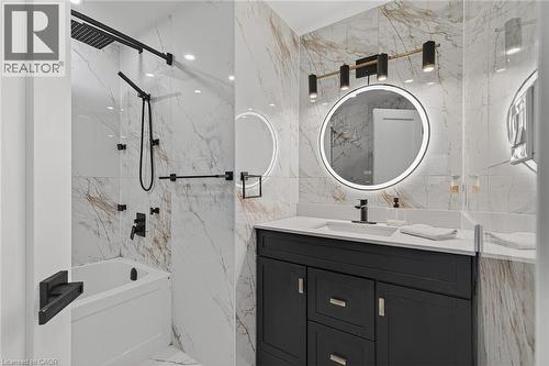 Bathroom featuring a single vanity with a white countertop and dark cabinetry, a backlit circular mirror, and a modern light fixture - 79 Holbrook Crescent, Cambridge, ON - Indoor Photo Showing Bathroom