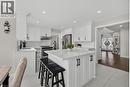 Bright kitchen featuring a central island with countertop seating, white shaker cabinetry, stainless steel appliances, and a matching stone backsplash - 79 Holbrook Crescent, Cambridge, ON  - Indoor 