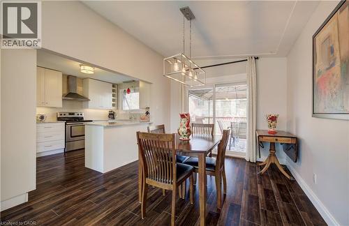 Kitchen and dining area featuring dark wood-finish flooring, white cabinetry, stainless steel appliances, and a sliding glass door - 172 Rennie Drive, Kitchener, ON - Indoor