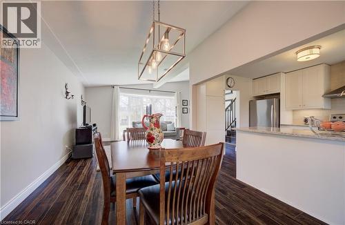 Open-concept living space featuring wood-finish flooring, a contemporary linear chandelier, and ample natural light from large windows - 172 Rennie Drive, Kitchener, ON - Indoor Photo Showing Dining Room