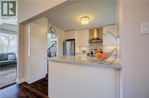 Modern kitchen featuring white cabinetry, light-toned countertops, stainless steel appliances, and a range hood - 172 Rennie Drive, Kitchener, ON - Indoor Photo Showing Kitchen