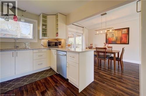 Kitchen featuring white cabinetry, light-toned countertops, a stainless steel dishwasher, wood-finish flooring, and a window above the sink - 172 Rennie Drive, Kitchener, ON - Indoor Photo Showing Kitchen