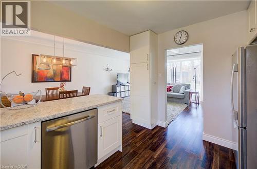 Kitchen featuring granite countertops, white cabinetry, stainless steel dishwasher, and rich wood-finish flooring - 172 Rennie Drive, Kitchener, ON - Indoor Photo Showing Kitchen