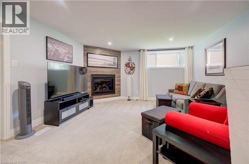 Carpeted living space featuring a corner fireplace with wood-finish paneling, recessed lighting, and a large egress window - 172 Rennie Drive, Kitchener, ON - Indoor Photo Showing Living Room With Fireplace