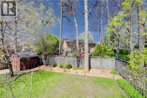 Expansive backyard featuring a lush lawn, mature trees, wood fence, garden shed, and varied landscaping - 172 Rennie Drive, Kitchener, ON - Outdoor