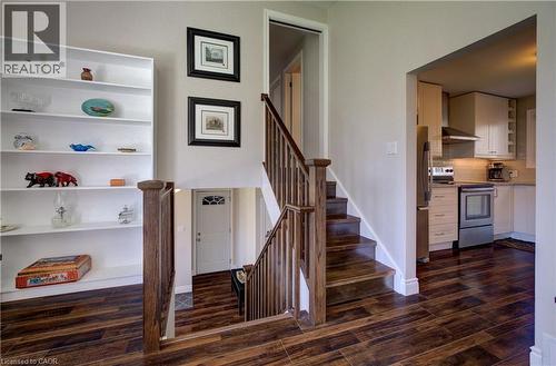 Rich wood-finish flooring throughout, featuring a hardwood staircase with matching banister and a built-in white shelving unit - 172 Rennie Drive, Kitchener, ON - Indoor Photo Showing Other Room
