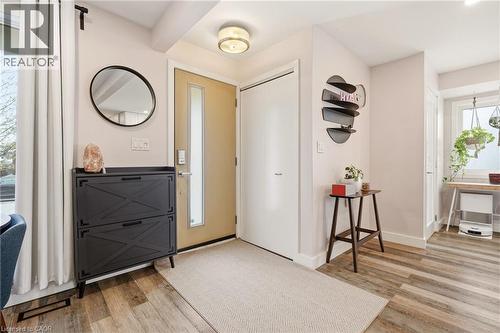 Entryway featuring wood-finish flooring, a contemporary ceiling light fixture, a neutral front door with a vertical window pane, and a white interior door - 30 Darlington Drive, Hamilton, ON - Indoor Photo Showing Other Room