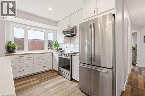 Modern kitchen featuring white cabinetry, light wood-finish countertops, stainless steel appliances, and wood-finish flooring - 30 Darlington Drive, Hamilton, ON - Indoor Photo Showing Kitchen With Upgraded Kitchen