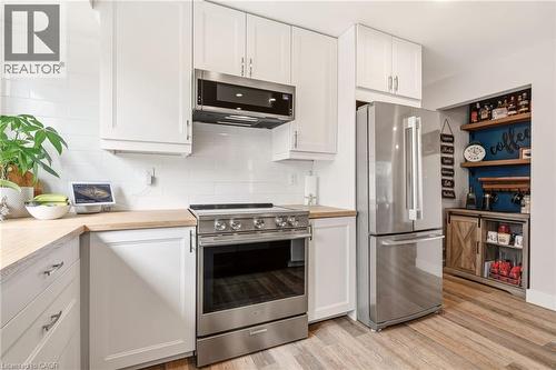 Bright kitchen featuring white shaker cabinetry, stainless steel appliances, wood-finish countertops, and a white subway tile backsplash - 30 Darlington Drive, Hamilton, ON - Indoor Photo Showing Kitchen