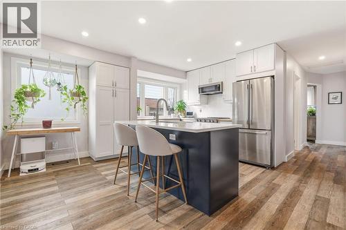 Kitchen featuring a large central island with seating, stainless steel appliances, white cabinetry, recessed lighting, and wood-finish flooring - 30 Darlington Drive, Hamilton, ON - Indoor