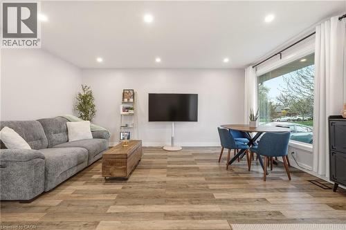 Open-concept living space featuring wood-finish flooring, recessed lighting, and a large picture window with white curtains - 30 Darlington Drive, Hamilton, ON - Indoor