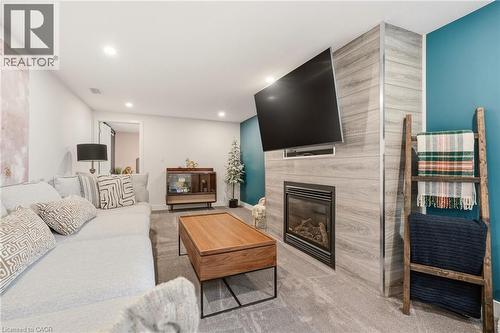 Living area featuring recessed lighting and a contemporary electric fireplace with a light-tone wood-finish surround - 30 Darlington Drive, Hamilton, ON - Indoor Photo Showing Living Room With Fireplace
