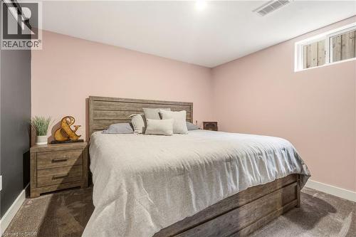 Carpeted room featuring a wood-finish bed frame, nightstand with dual drawers, and a high-set window - 30 Darlington Drive, Hamilton, ON - Indoor Photo Showing Bedroom