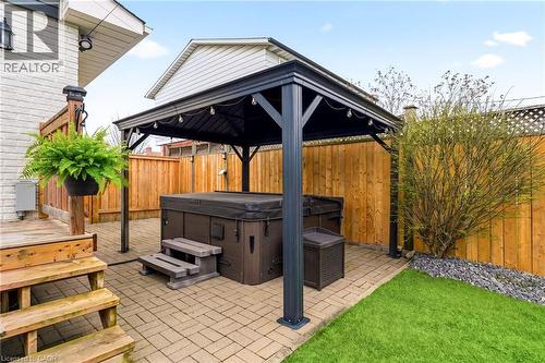 Private backyard featuring a hot tub under a dark metal gazebo with string lighting - 30 Darlington Drive, Hamilton, ON - Outdoor With Deck Patio Veranda With Exterior