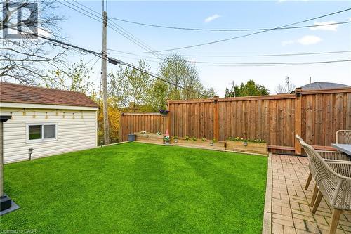 Fenced backyard featuring a manicured lawn, brick paver patio, and raised garden beds - 30 Darlington Drive, Hamilton, ON - Outdoor