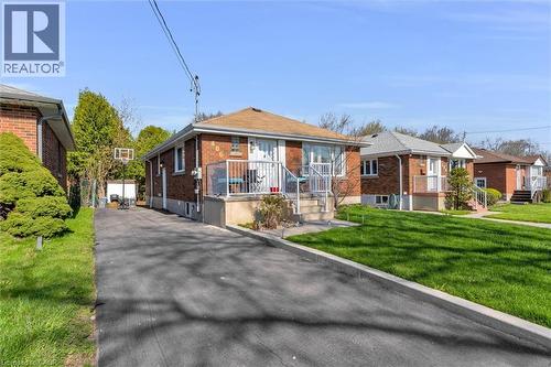 Brick exterior residence featuring a front porch with white railings and an asphalt driveway - 406 East 43Rd Street, Hamilton, ON - Outdoor