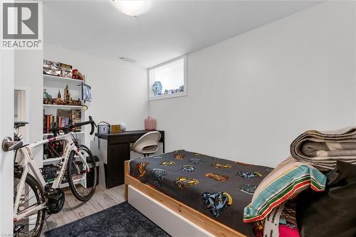Compact room featuring wood-finish flooring, a white built-in shelving unit, a window with horizontal blinds, and a flush-mount ceiling light fixture - 406 East 43Rd Street, Hamilton, ON - Indoor