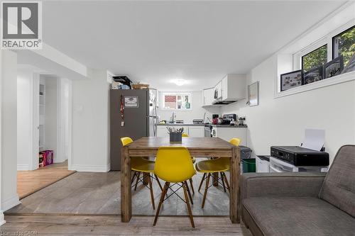 Combined living and kitchen area featuring wood-finish flooring, white cabinetry, a built-in oven, and a double-basin sink - 406 East 43Rd Street, Hamilton, ON - Indoor