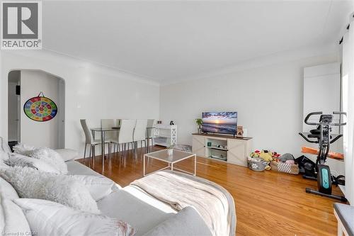 Open-concept living space featuring wood-finish flooring, white walls, crown molding, and an arched doorway - 406 East 43Rd Street, Hamilton, ON - Indoor