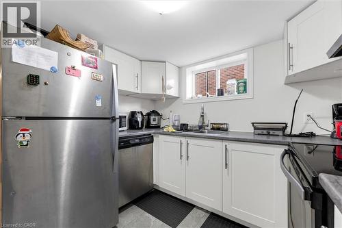 Kitchen featuring white cabinetry, stainless steel appliances, a window with exterior brick exposure, and grey countertops - 406 East 43Rd Street, Hamilton, ON - Indoor Photo Showing Kitchen With Double Sink