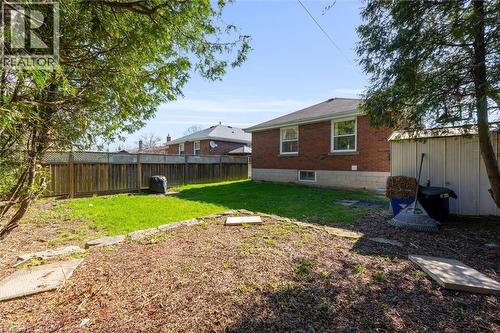 Spacious backyard featuring a section of green lawn, mature trees, and a wooden privacy fence - 406 East 43Rd Street, Hamilton, ON - Outdoor With Backyard